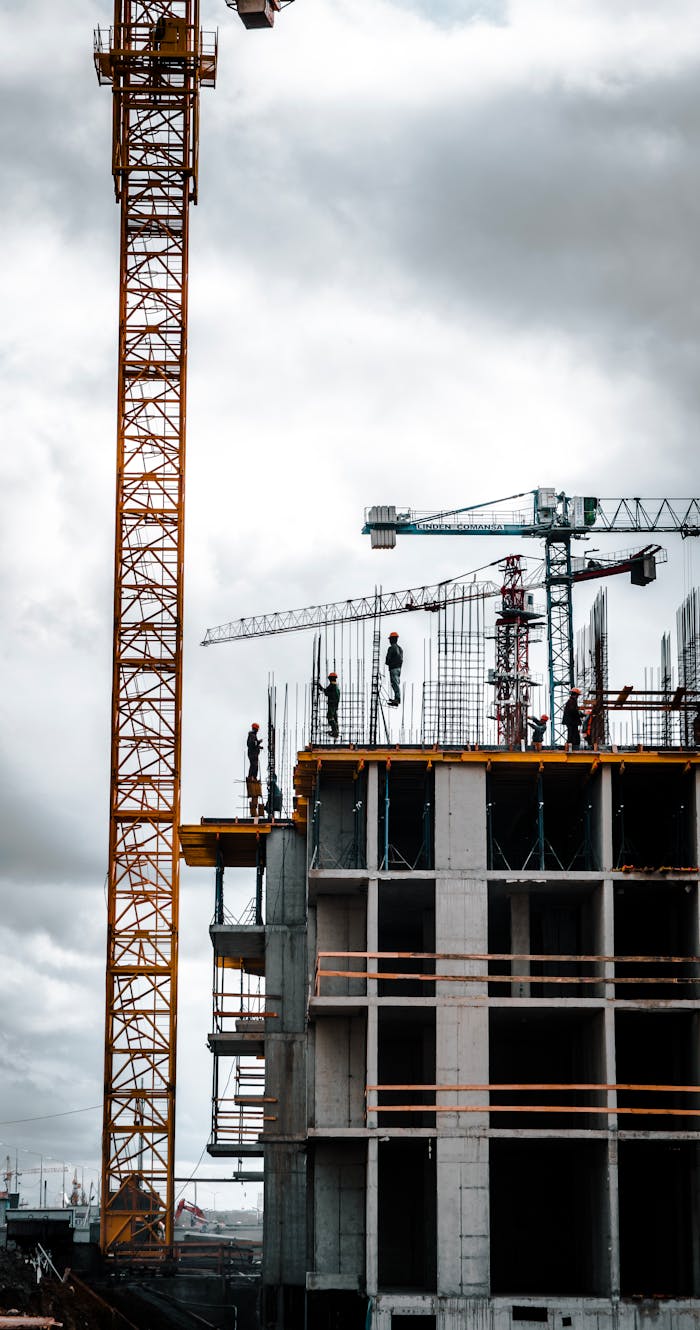 Vertical view of a construction site with cranes and workers building a skyscraper.